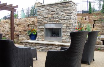 A backyard patio with an outdoor fireplace and comfortable furniture.