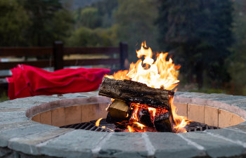 outdoor fireplace with a bright yellow flame in a fire pit and autumn forest background, 